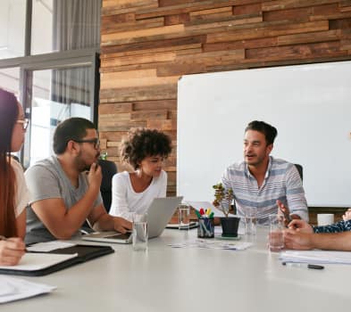 Two men collaborating on a laptop in a modern office setting, focused on their work.