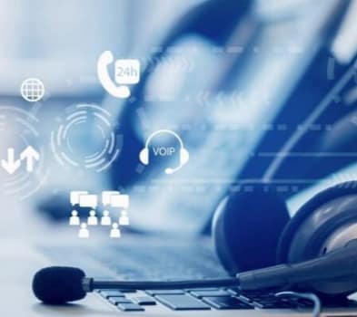 A woman wearing headphones sits at a desk in an office, focused on her work.